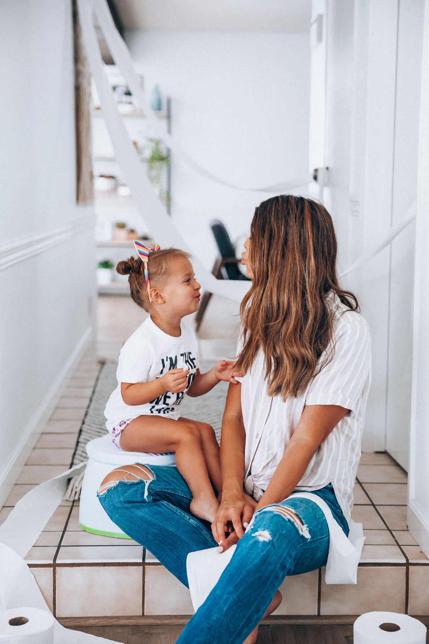 Our Potty Training Tips + Journey by popular San Francisco lifestyle blog, The Girl in the Yellow Dress: image of a woman and her daughter sitting on the ground with some toilet paper and a potty training toilet.