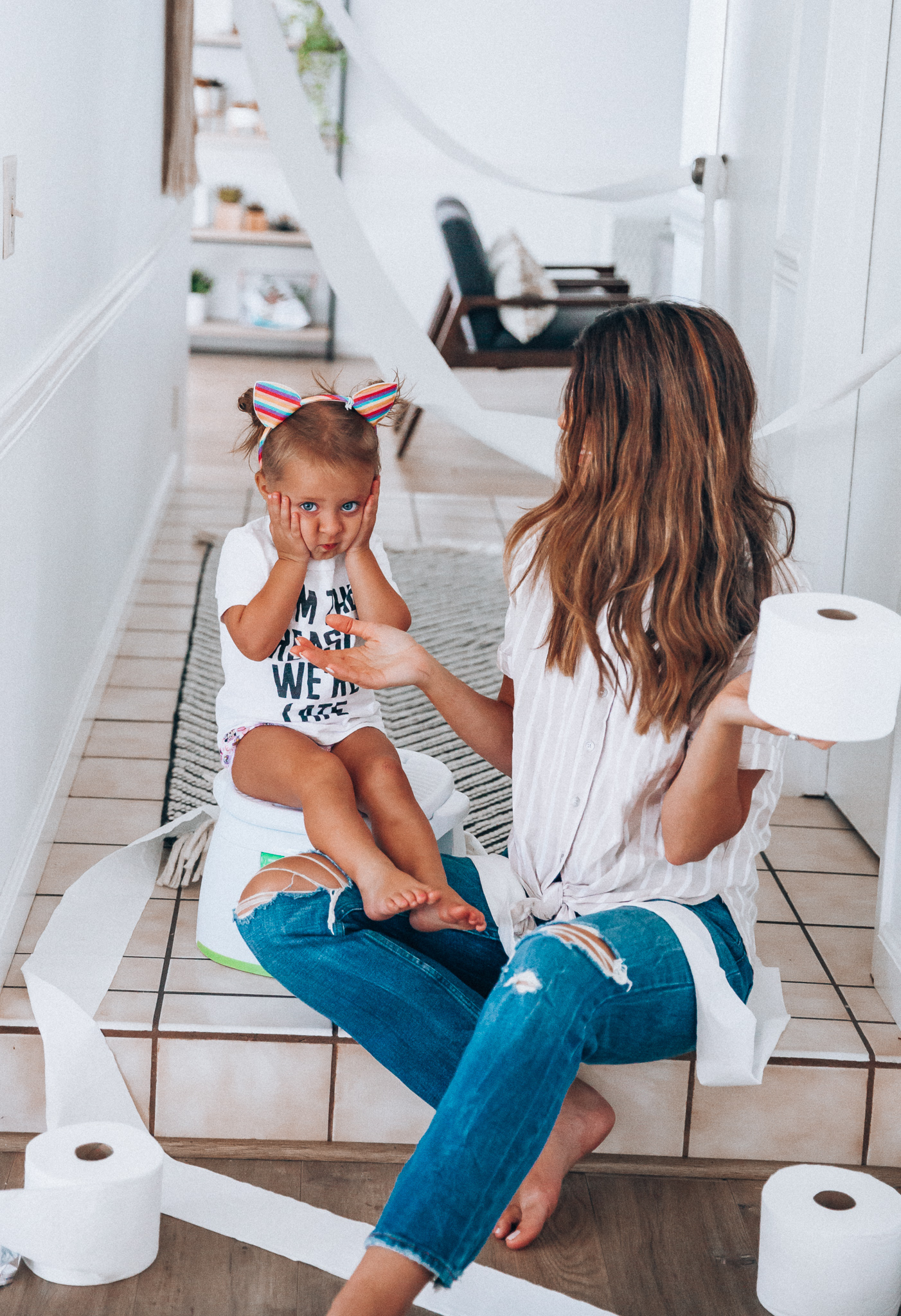 Our Potty Training Tips + Journey by popular San Francisco lifestyle blog, The Girl in the Yellow Dress: image of a woman and her daughter sitting on the ground with some toilet paper and a potty training toilet.