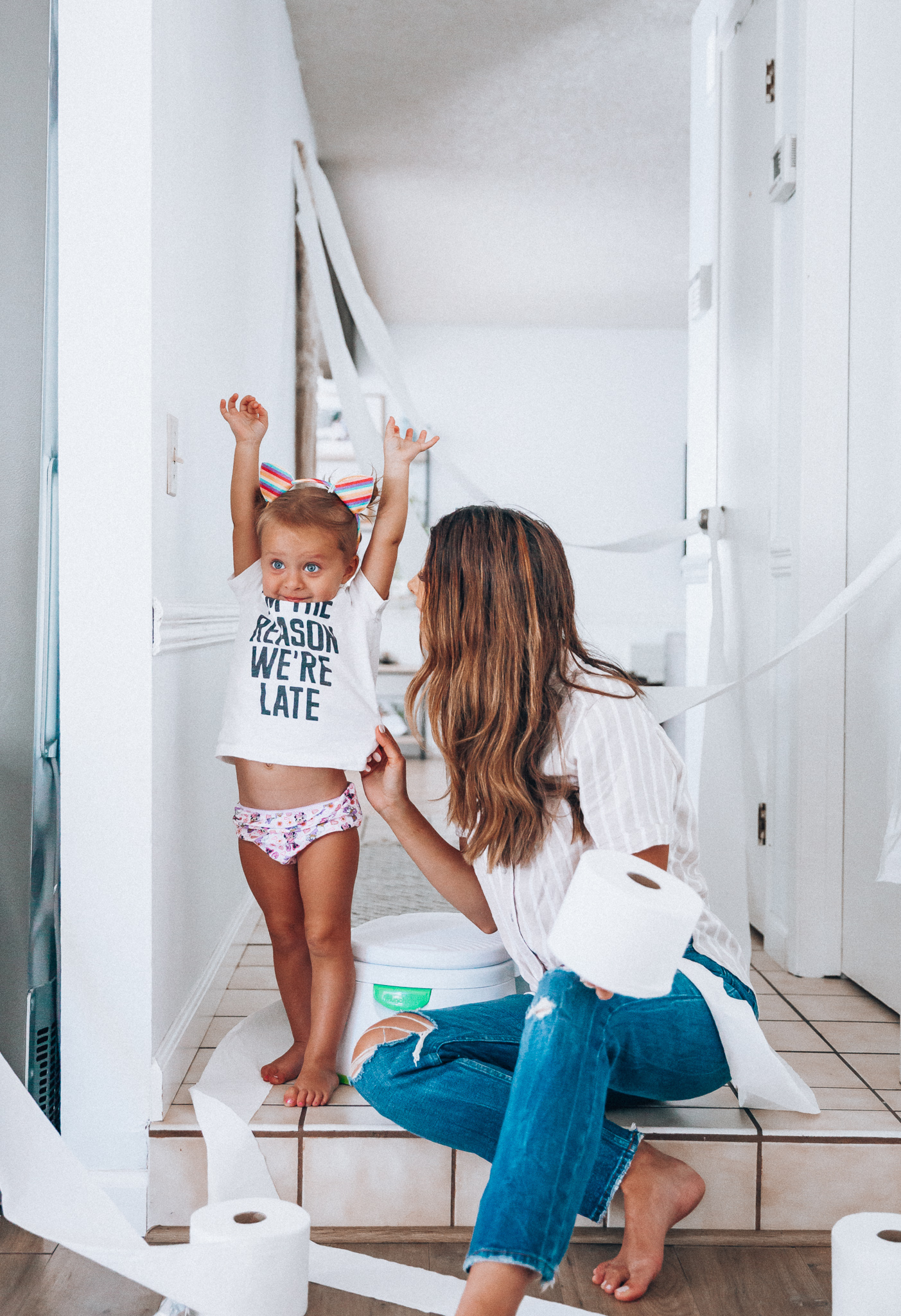 Our Potty Training Tips + Journey by popular San Francisco lifestyle blog, The Girl in the Yellow Dress: image of a woman and her daughter sitting on the ground with some toilet paper and a potty training toilet.