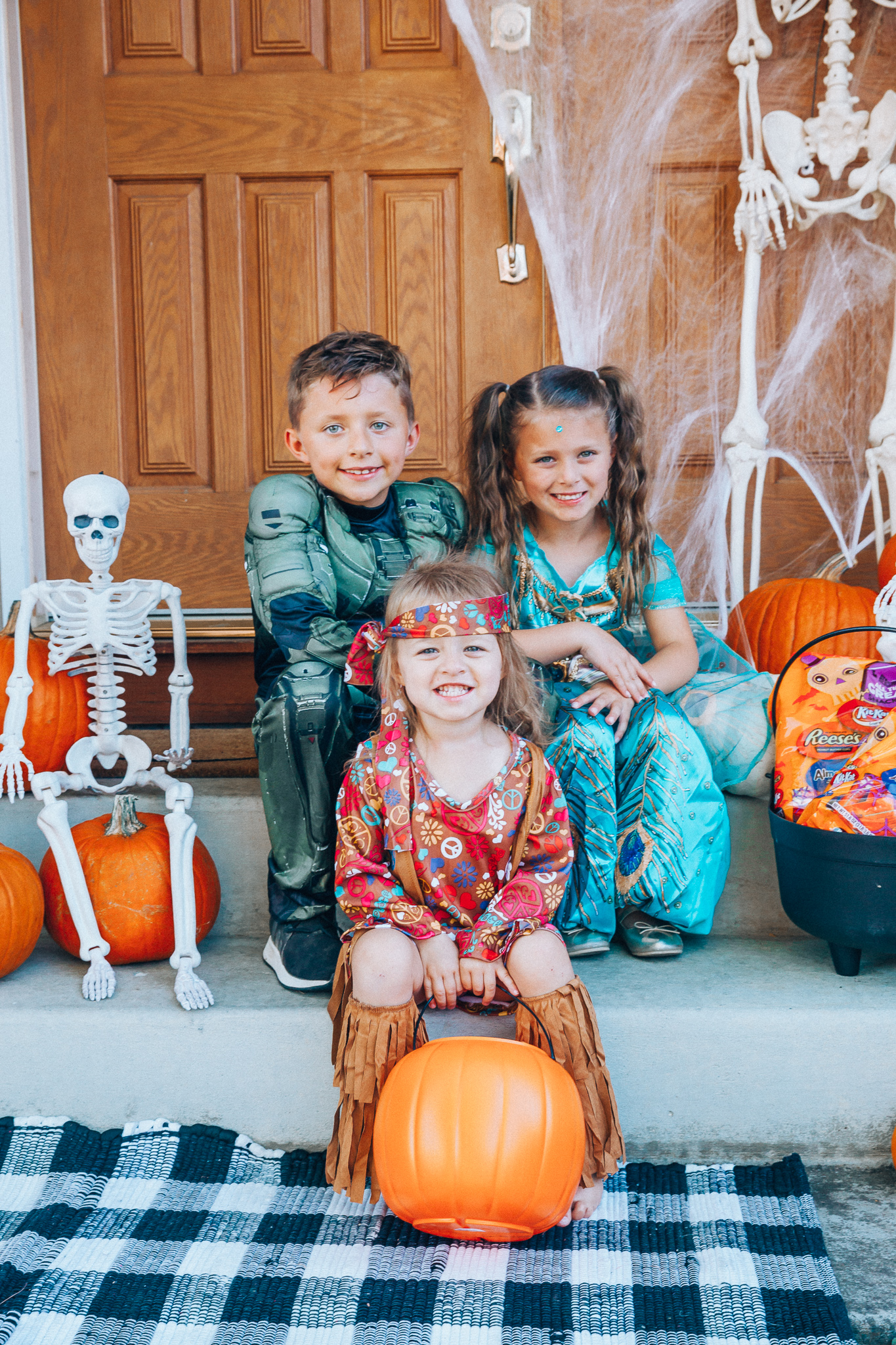 Spooky Halloween Front Porch Decor from Walmart by popular San Francisco life and style blog, The Girl in the Yellow Dress: image of a family standing on their front porch that's decorated with a Walmart 5ft Full Body Skeleton Props with Movable Joints for Halloween Party Decoration, Halloween Dutch Kettle Cauldron 14 Inch Black Plastic Party Accessory (1/Pkg) Pkg/1  Report incorrect product info or prohibited items Halloween Dutch Kettle Cauldron 14 Inch Black Plastic Party Accessory, Walmart Poseable Skeleton 20in Halloween Decoration, Pumpkins, and Walmart Stretchable Spider Web and Spider Halloween Decoration and wearing a Walmart Girl's Jasmine Teal Classic Halloween Costume, Walmart 60's Hippie with Fringe Child Halloween Costume, Walmart Halo Boys' Master Chief Classic Muscle Costume, Walmart Sequin cat ears, Walmart Jordache  Women's Super Soft Mid Rise Skinny Jean, Walmart Seven Dials  Womens Seven Dials Teatime Sock Booties, and Walmart TheLovely  Women's Long Sleeve Crew Neck Basic T-Shirt Top.