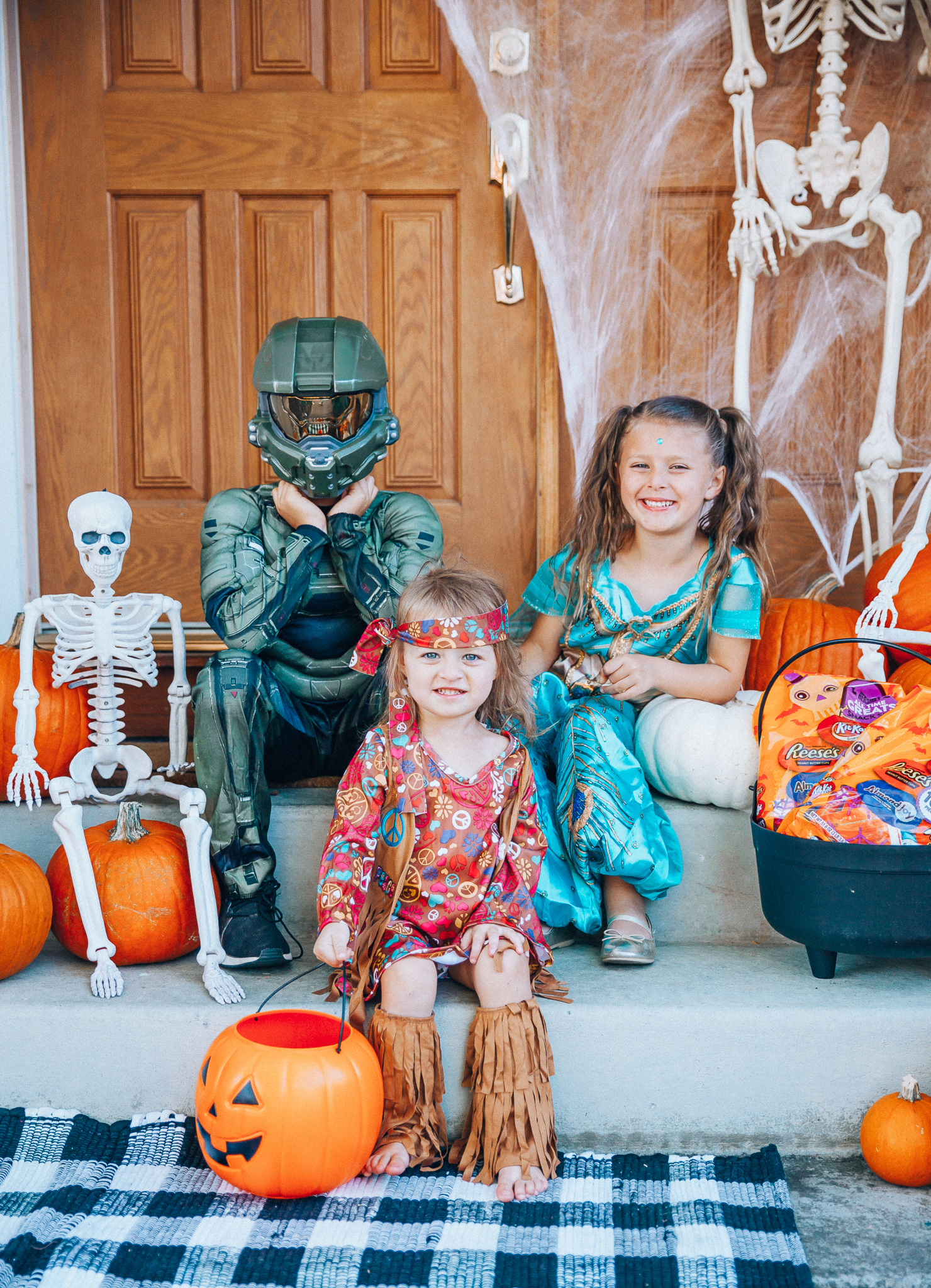 Spooky Halloween Front Porch Decor from Walmart by popular San Francisco life and style blog, The Girl in the Yellow Dress: image of a family standing on their front porch that's decorated with a Walmart 5ft Full Body Skeleton Props with Movable Joints for Halloween Party Decoration, Halloween Dutch Kettle Cauldron 14 Inch Black Plastic Party Accessory (1/Pkg) Pkg/1  Report incorrect product info or prohibited items Halloween Dutch Kettle Cauldron 14 Inch Black Plastic Party Accessory, Walmart Poseable Skeleton 20in Halloween Decoration, Pumpkins, and Walmart Stretchable Spider Web and Spider Halloween Decoration and wearing a Walmart Girl's Jasmine Teal Classic Halloween Costume, Walmart 60's Hippie with Fringe Child Halloween Costume, Walmart Halo Boys' Master Chief Classic Muscle Costume, Walmart Sequin cat ears, Walmart Jordache  Women's Super Soft Mid Rise Skinny Jean, Walmart Seven Dials  Womens Seven Dials Teatime Sock Booties, and Walmart TheLovely  Women's Long Sleeve Crew Neck Basic T-Shirt Top.