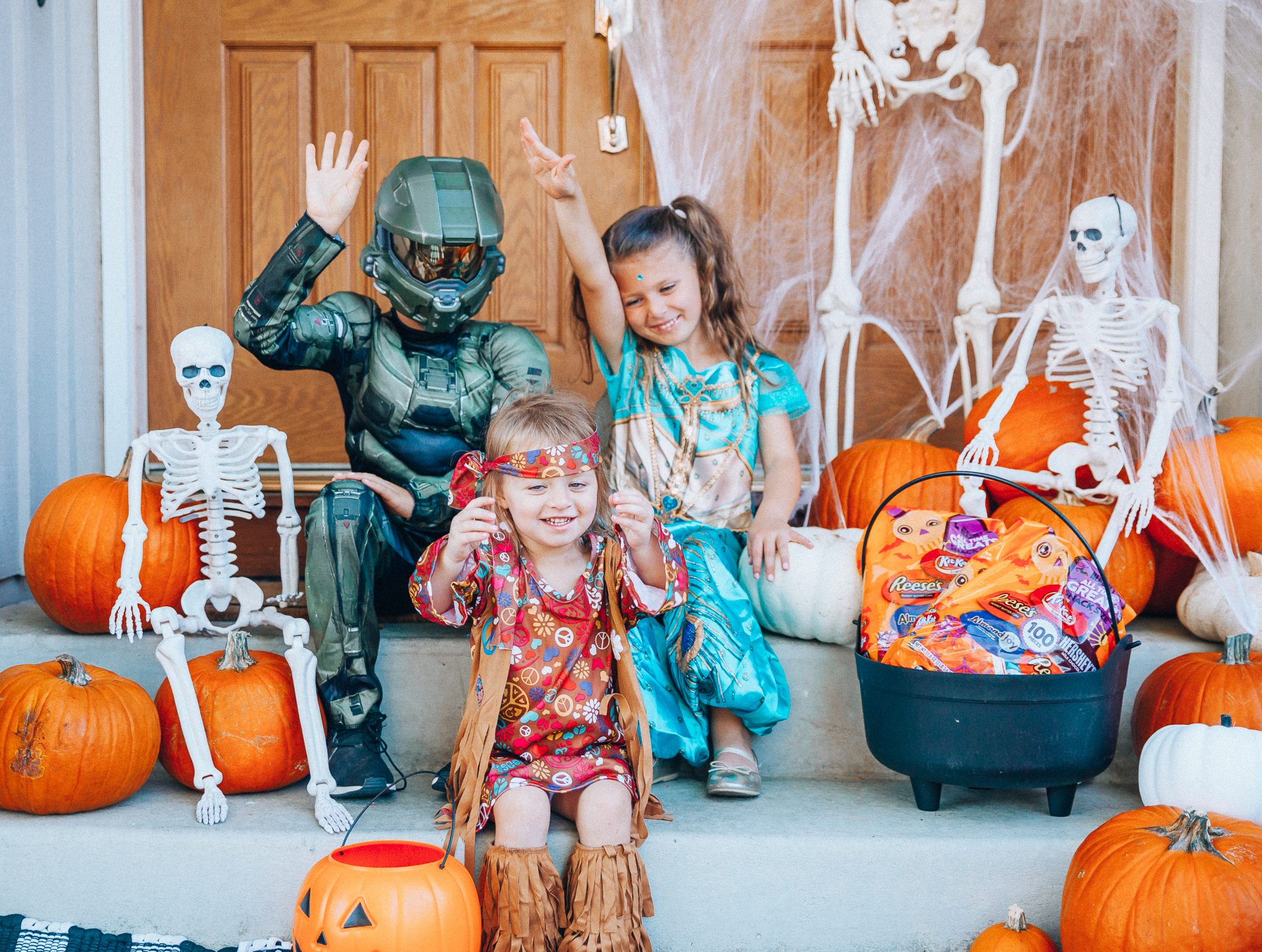 Spooky Halloween Front Porch Decor from Walmart by popular San Francisco life and style blog, The Girl in the Yellow Dress: image of a family standing on their front porch that's decorated with a Walmart 5ft Full Body Skeleton Props with Movable Joints for Halloween Party Decoration, Halloween Dutch Kettle Cauldron 14 Inch Black Plastic Party Accessory (1/Pkg) Pkg/1  Report incorrect product info or prohibited items Halloween Dutch Kettle Cauldron 14 Inch Black Plastic Party Accessory, Walmart Poseable Skeleton 20in Halloween Decoration, Pumpkins, and Walmart Stretchable Spider Web and Spider Halloween Decoration and wearing a Walmart Girl's Jasmine Teal Classic Halloween Costume, Walmart 60's Hippie with Fringe Child Halloween Costume, Walmart Halo Boys' Master Chief Classic Muscle Costume, Walmart Sequin cat ears, Walmart Jordache  Women's Super Soft Mid Rise Skinny Jean, Walmart Seven Dials  Womens Seven Dials Teatime Sock Booties, and Walmart TheLovely  Women's Long Sleeve Crew Neck Basic T-Shirt Top.