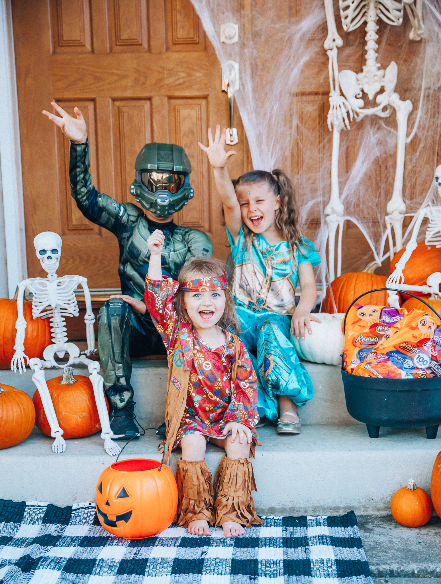 Spooky Halloween Front Porch Decor from Walmart by popular San Francisco life and style blog, The Girl in the Yellow Dress: image of a family standing on their front porch that's decorated with a Walmart 5ft Full Body Skeleton Props with Movable Joints for Halloween Party Decoration, Halloween Dutch Kettle Cauldron 14 Inch Black Plastic Party Accessory (1/Pkg) Pkg/1  Report incorrect product info or prohibited items Halloween Dutch Kettle Cauldron 14 Inch Black Plastic Party Accessory, Walmart Poseable Skeleton 20in Halloween Decoration, Pumpkins, and Walmart Stretchable Spider Web and Spider Halloween Decoration and wearing a Walmart Girl's Jasmine Teal Classic Halloween Costume, Walmart 60's Hippie with Fringe Child Halloween Costume, Walmart Halo Boys' Master Chief Classic Muscle Costume, Walmart Sequin cat ears, Walmart Jordache  Women's Super Soft Mid Rise Skinny Jean, Walmart Seven Dials  Womens Seven Dials Teatime Sock Booties, and Walmart TheLovely  Women's Long Sleeve Crew Neck Basic T-Shirt Top.