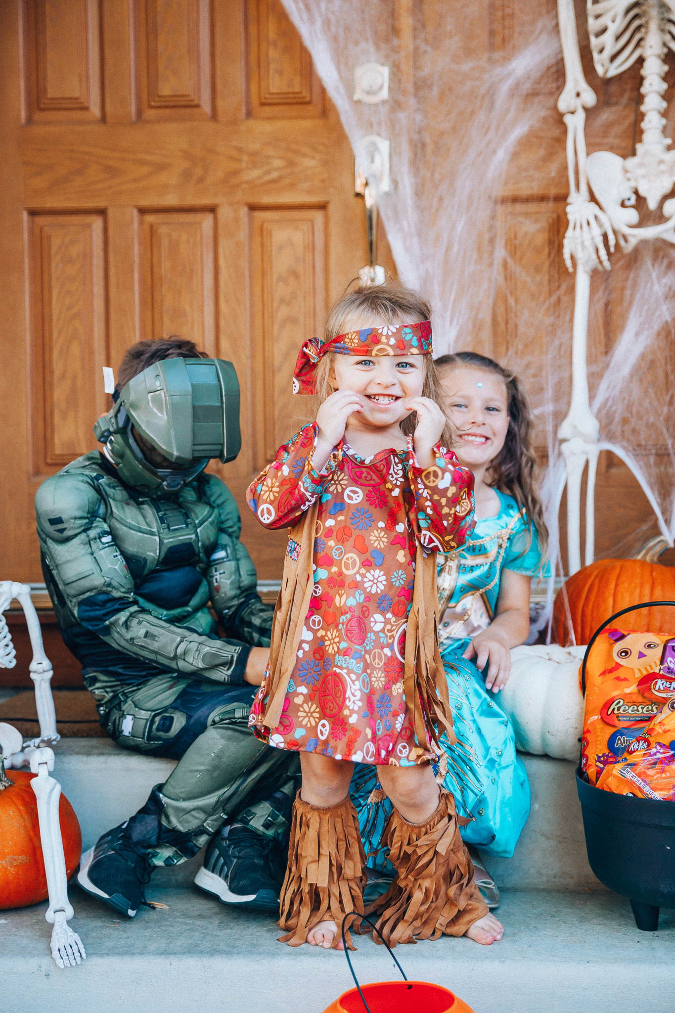 Spooky Halloween Front Porch Decor from Walmart by popular San Francisco life and style blog, The Girl in the Yellow Dress: image of a family standing on their front porch that's decorated with a Walmart 5ft Full Body Skeleton Props with Movable Joints for Halloween Party Decoration, Halloween Dutch Kettle Cauldron 14 Inch Black Plastic Party Accessory (1/Pkg) Pkg/1  Report incorrect product info or prohibited items Halloween Dutch Kettle Cauldron 14 Inch Black Plastic Party Accessory, Walmart Poseable Skeleton 20in Halloween Decoration, Pumpkins, and Walmart Stretchable Spider Web and Spider Halloween Decoration and wearing a Walmart Girl's Jasmine Teal Classic Halloween Costume, Walmart 60's Hippie with Fringe Child Halloween Costume, Walmart Halo Boys' Master Chief Classic Muscle Costume, Walmart Sequin cat ears, Walmart Jordache  Women's Super Soft Mid Rise Skinny Jean, Walmart Seven Dials  Womens Seven Dials Teatime Sock Booties, and Walmart TheLovely  Women's Long Sleeve Crew Neck Basic T-Shirt Top.