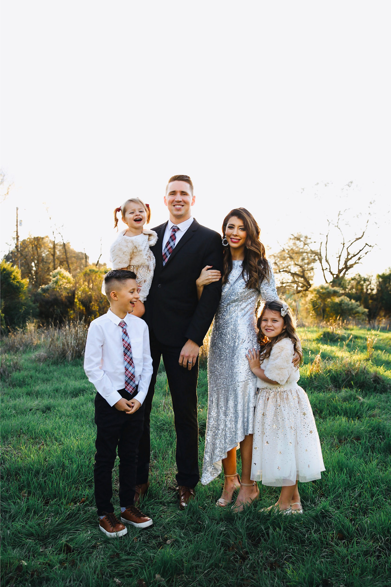 Merry Christmas Wishes 2019 by popular San Francisco life and style blog, The Girl in the Yellow Dress: image of a family standing together outside in a grassy field and wearing Nordstrom Sam Edelman Yaro Ankle Strap Sandals, H&M Earrings with Beads, Express Slim Solid Wrinkle-Resistant Performance Dress Shirt, Nordstrom Topman Skinny Fit Textured Dress Pants, Nordstrom Magnanni 'Lamont' Cap Toe Oxford, Nordstrom Ted Baker London Plaid Silk Tie, H&M Sequined Tulle Dress, and Amazon THEE BRON Girl's Toddler/Little Kid Ballet Mary Jane Flat Shoes.