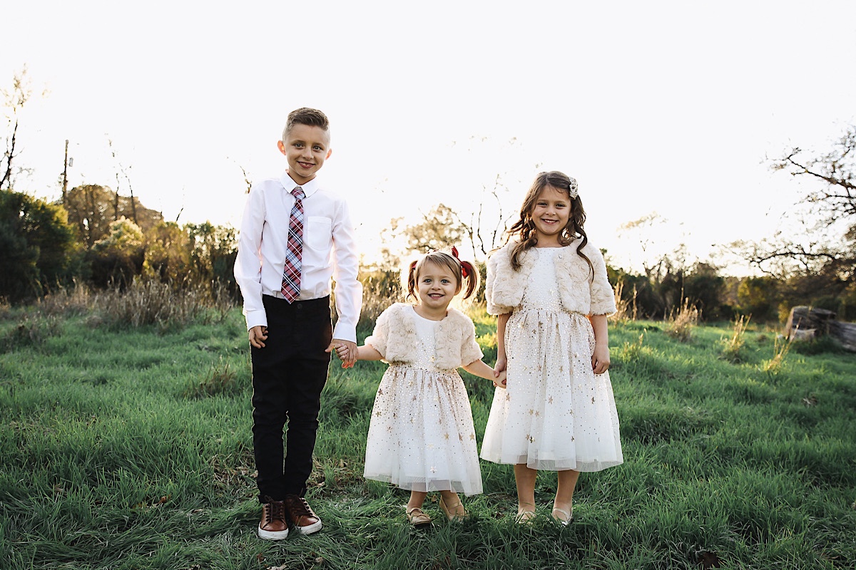 Merry Christmas Wishes 2019 by popular San Francisco life and style blog, The Girl in the Yellow Dress: image of a brother and two sisters standing together outside in a grassy field and wearing H&M Sequined Tulle Dress, and Amazon THEE BRON Girl's Toddler/Little Kid Ballet Mary Jane Flat Shoes.