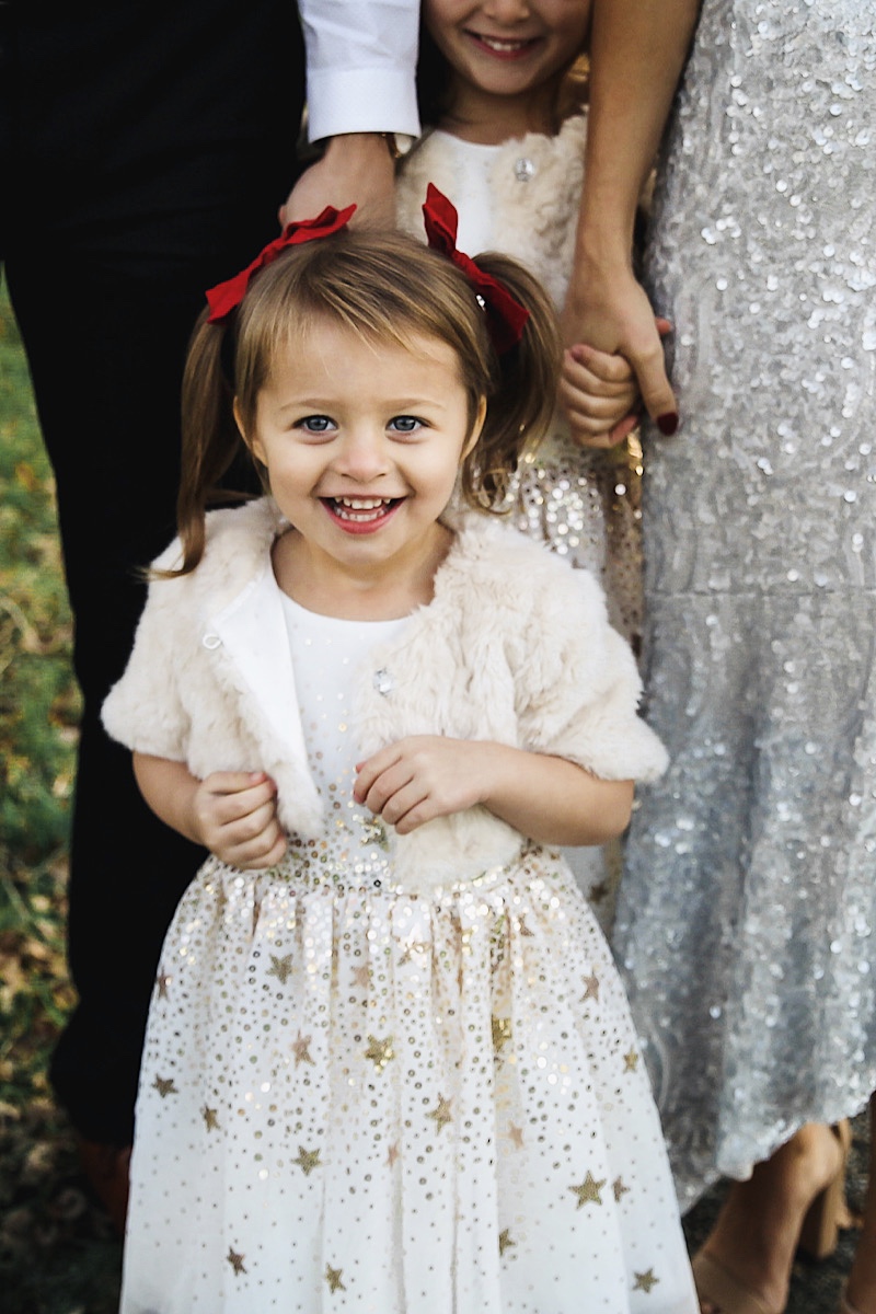 Merry Christmas Wishes 2019 by popular San Francisco life and style blog, The Girl in the Yellow Dress: image of a family standing together outside in a grassy field and wearing Nordstrom Sam Edelman Yaro Ankle Strap Sandals, H&M Earrings with Beads, Express Slim Solid Wrinkle-Resistant Performance Dress Shirt, Nordstrom Topman Skinny Fit Textured Dress Pants, Nordstrom Magnanni 'Lamont' Cap Toe Oxford, Nordstrom Ted Baker London Plaid Silk Tie, H&M Sequined Tulle Dress, and Amazon THEE BRON Girl's Toddler/Little Kid Ballet Mary Jane Flat Shoes.