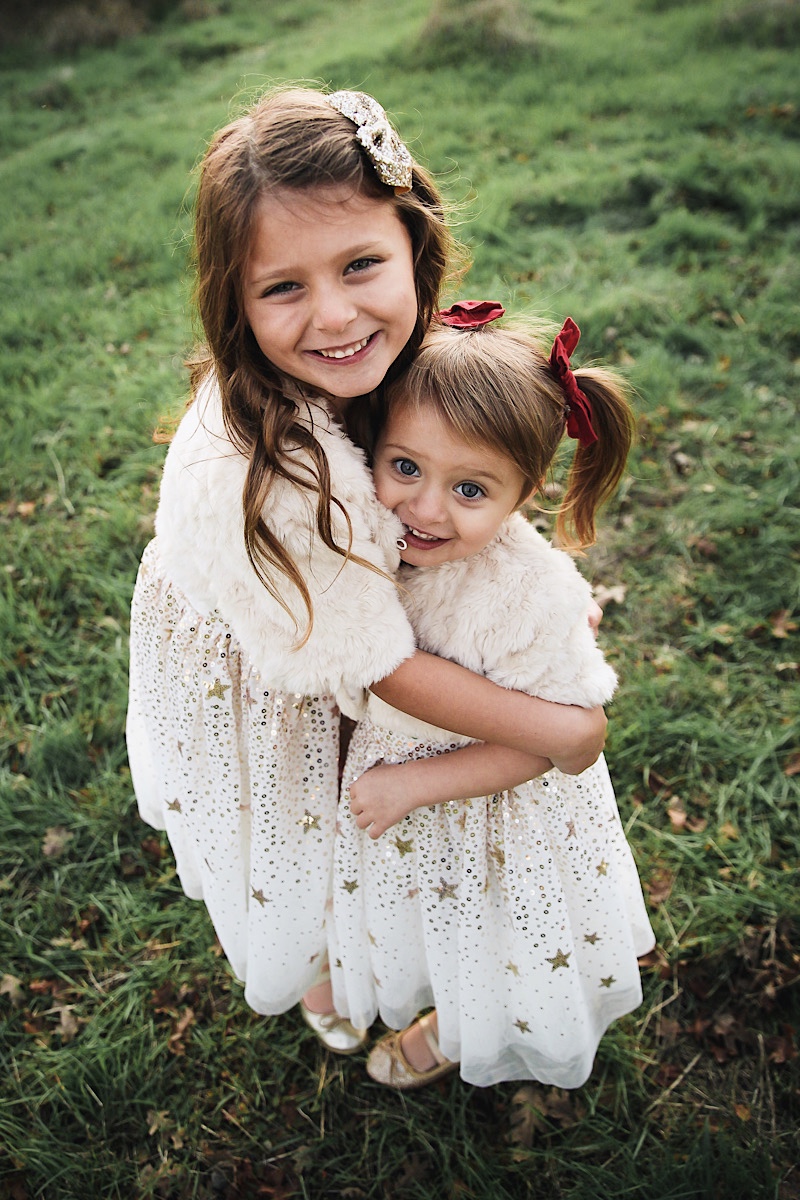 Merry Christmas Wishes 2019 by popular San Francisco life and style blog, The Girl in the Yellow Dress: image of two girls standing together outside in a grassy field and wearing H&M Sequined Tulle Dress and Amazon THEE BRON Girl's Toddler/Little Kid Ballet Mary Jane Flat Shoes.