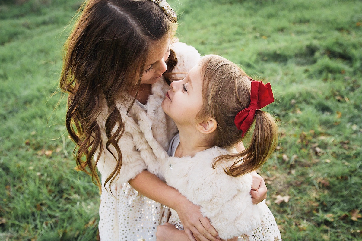 Merry Christmas Wishes 2019 by popular San Francisco life and style blog, The Girl in the Yellow Dress: image of two girls standing together outside in a grassy field and wearing H&M Sequined Tulle Dress and Amazon THEE BRON Girl's Toddler/Little Kid Ballet Mary Jane Flat Shoes.