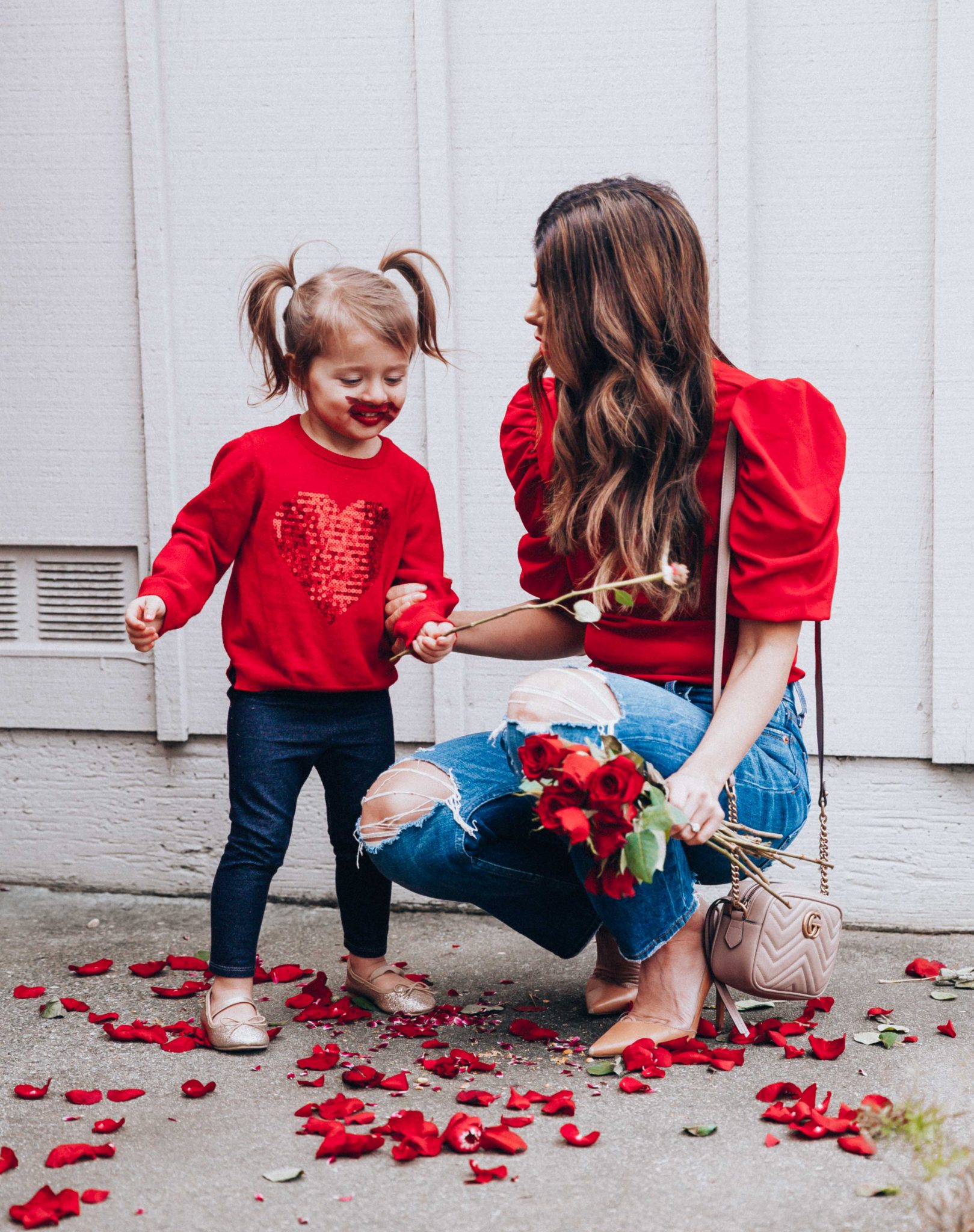 Mommy and Me Valentine's Day Outfits by popular San Francisco fashion blog, The Girl in the Yellow Dress: image of a mom and her daughter wearing an Amazon ROMWE Women's Summer Short Sleeve Mock Neck Casual Blouse Top, Abercrombie and Fitch High Rise Mom Jeans, Nordstrom Jaina Pump SAM EDELMAN, Nordstrom Matelassé Leather Shoulder Bag GUCCI, Amazon Carter's Valentines Day Red Heart Sweater with Sequins for Toddler Girls, Target Toddler Girls' Faux Denim Leggings, and Amazon THEE BRON Girl's Toddler/Little Kid Ballet Mary Jane Flat Shoes.