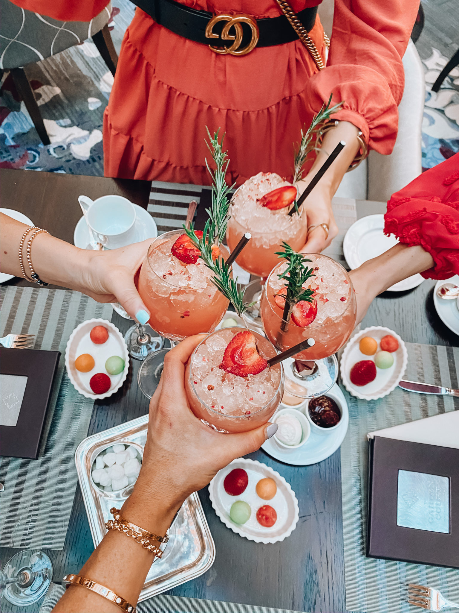 The Palace Hotel San Francisco by popular San Francisco blogger, The Girl in the Yellow Dress: image of 4 women standing together in the Palace Hotel San Francisco restaurant clinking glasses with strawberry drinks in them and wearing a Anthropologie Amber Tiered Tunic, Sam Edelman Daffodil Heel Sandal, Saks Fifth Avenue Gucci Marmont Matelasse mini purse, and Anthropologie Amal Textured Mini Dress.