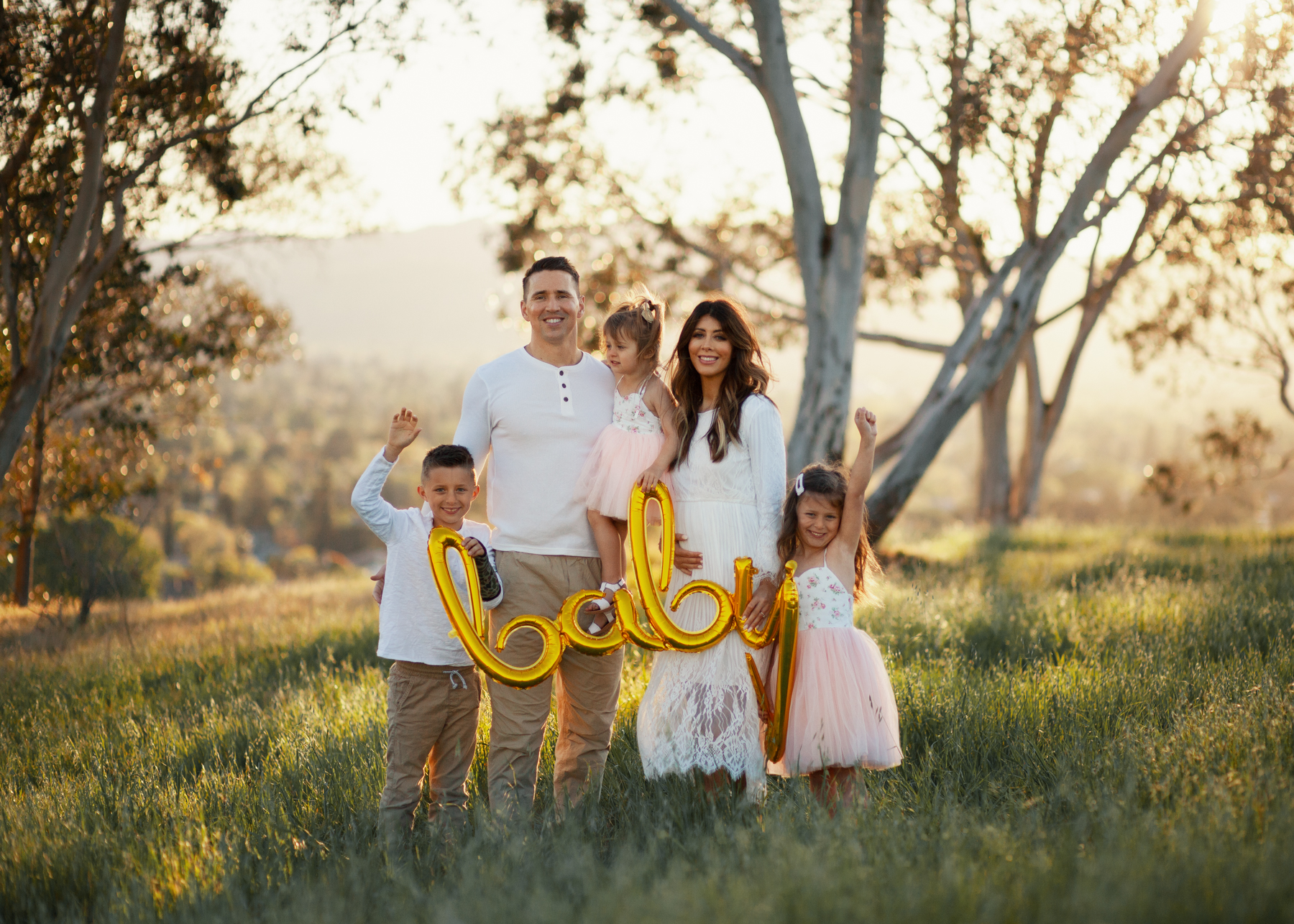 Family Pregnancy Announcement by popular San Francisco lifestyle blog, The Girl in the Yellow Dress: image of a family standing in a field, holding a gold baby balloon and wearing a Nordstrom Yaro Ankle Strap Sandal SAM EDELMAN, Old Navy Soft-Washed Long-Sleeve Henley for Men, Aerie AE NE(X)T LEVEL KHAKI JOGGER, Nordstrom GrandPro Low Top Sneaker COLE HAAN, Amazon Flofallzique Baby Girls Dress Toddler Tutu Infant Floral Sundress Tulle Wedding Dress, Freshly Picked White Patent Malibu, Old Navy Softest Crew-Neck Long-Sleeve Tee for Boys, and Old Navy Built-In Flex Twill Joggers for Boys.