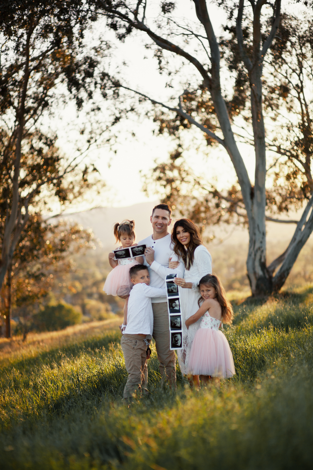 Family Pregnancy Announcement by popular San Francisco lifestyle blog, The Girl in the Yellow Dress: image of a family standing in a field, holding ultra sound photos and wearing a Nordstrom Yaro Ankle Strap Sandal SAM EDELMAN, Old Navy Soft-Washed Long-Sleeve Henley for Men, Aerie AE NE(X)T LEVEL KHAKI JOGGER, Nordstrom GrandPro Low Top Sneaker COLE HAAN, Amazon Flofallzique Baby Girls Dress Toddler Tutu Infant Floral Sundress Tulle Wedding Dress, Freshly Picked White Patent Malibu, Old Navy Softest Crew-Neck Long-Sleeve Tee for Boys, and Old Navy Built-In Flex Twill Joggers for Boys.