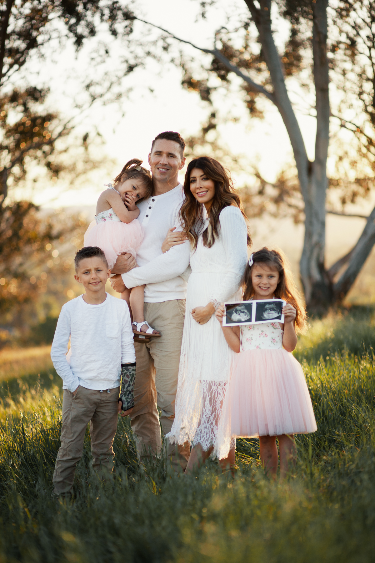 Family Pregnancy Announcement by popular San Francisco lifestyle blog, The Girl in the Yellow Dress: image of a family standing in a field, holding a gold baby balloon and wearing a Nordstrom Yaro Ankle Strap Sandal SAM EDELMAN, Old Navy Soft-Washed Long-Sleeve Henley for Men, Aerie AE NE(X)T LEVEL KHAKI JOGGER, Nordstrom GrandPro Low Top Sneaker COLE HAAN, Amazon Flofallzique Baby Girls Dress Toddler Tutu Infant Floral Sundress Tulle Wedding Dress, Freshly Picked White Patent Malibu, Old Navy Softest Crew-Neck Long-Sleeve Tee for Boys, and Old Navy Built-In Flex Twill Joggers for Boys.