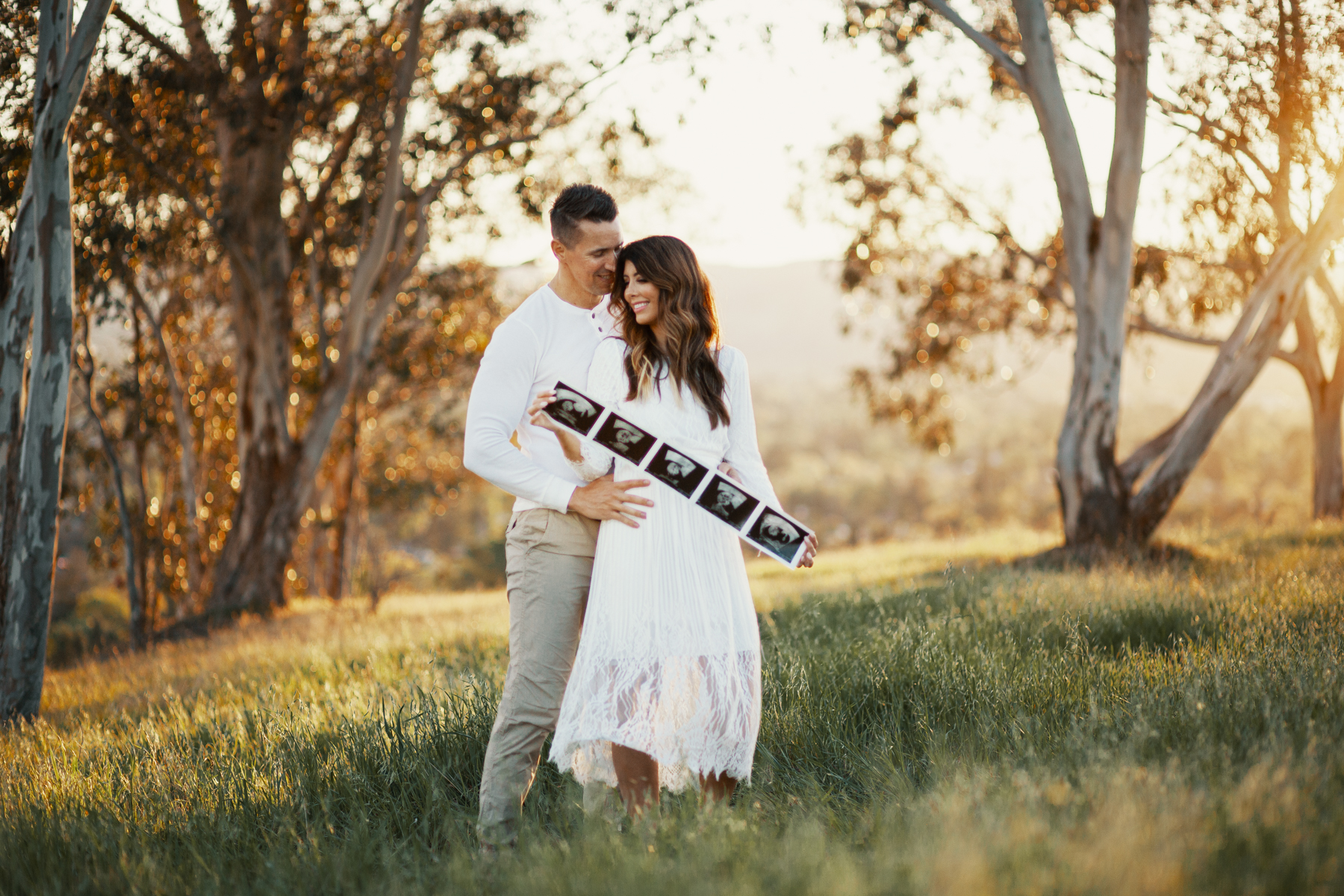 Family Pregnancy Announcement by popular San Francisco lifestyle blog, The Girl in the Yellow Dress: image of a husband and wife standing in a field, holding ultra sound photos and wearing a Nordstrom Yaro Ankle Strap Sandal SAM EDELMAN, Old Navy Soft-Washed Long-Sleeve Henley for Men, Aerie AE NE(X)T LEVEL KHAKI JOGGER, and Nordstrom GrandPro Low Top Sneaker COLE HAAN.