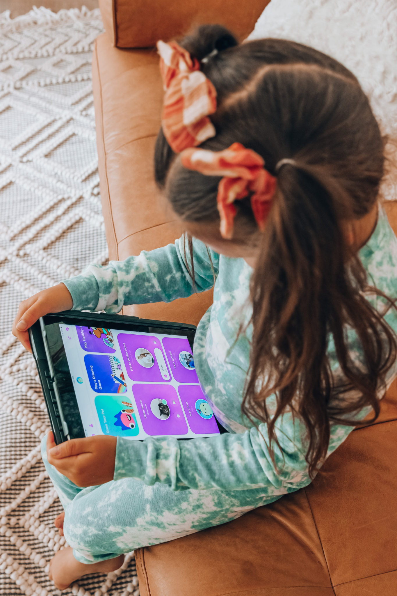 Messenger Kids Review by popular San Francisco lifestyle blog,The Girl in the Yellow Dress: image of a young girl wearing a tie dye pajama set and holding a tablet. 