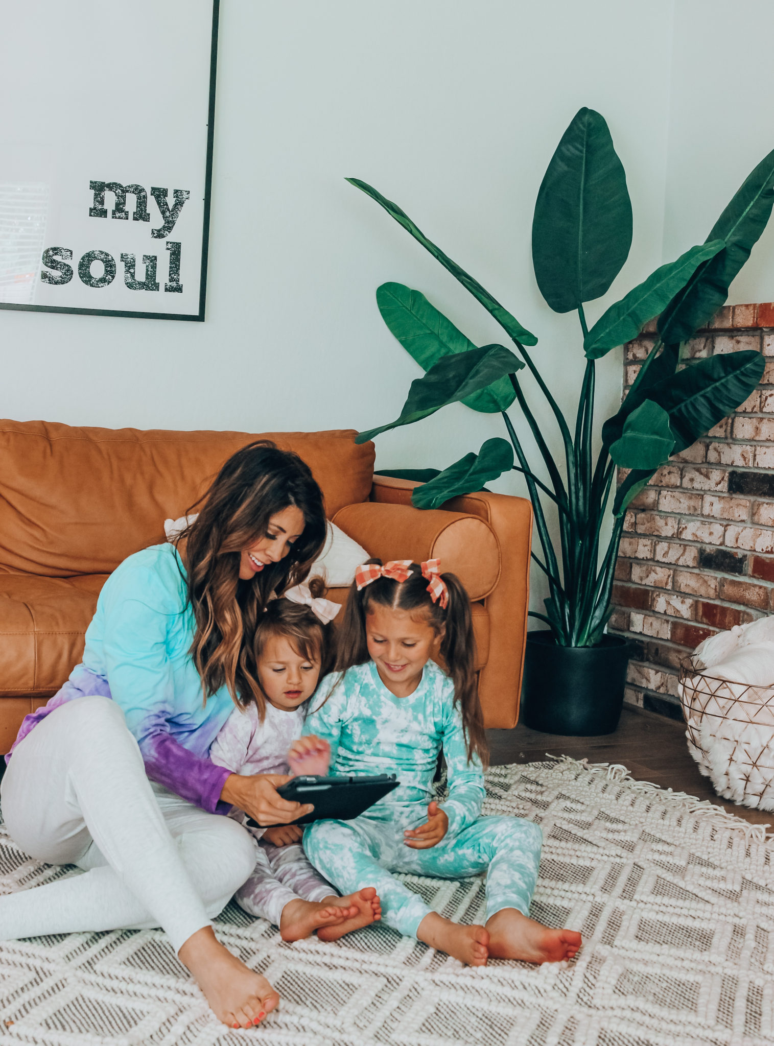 Messenger Kids Review by popular San Francisco lifestyle blog,The Girl in the Yellow Dress: image of a mom and her two young daughters sitting together on the floor and holding a tablet. 