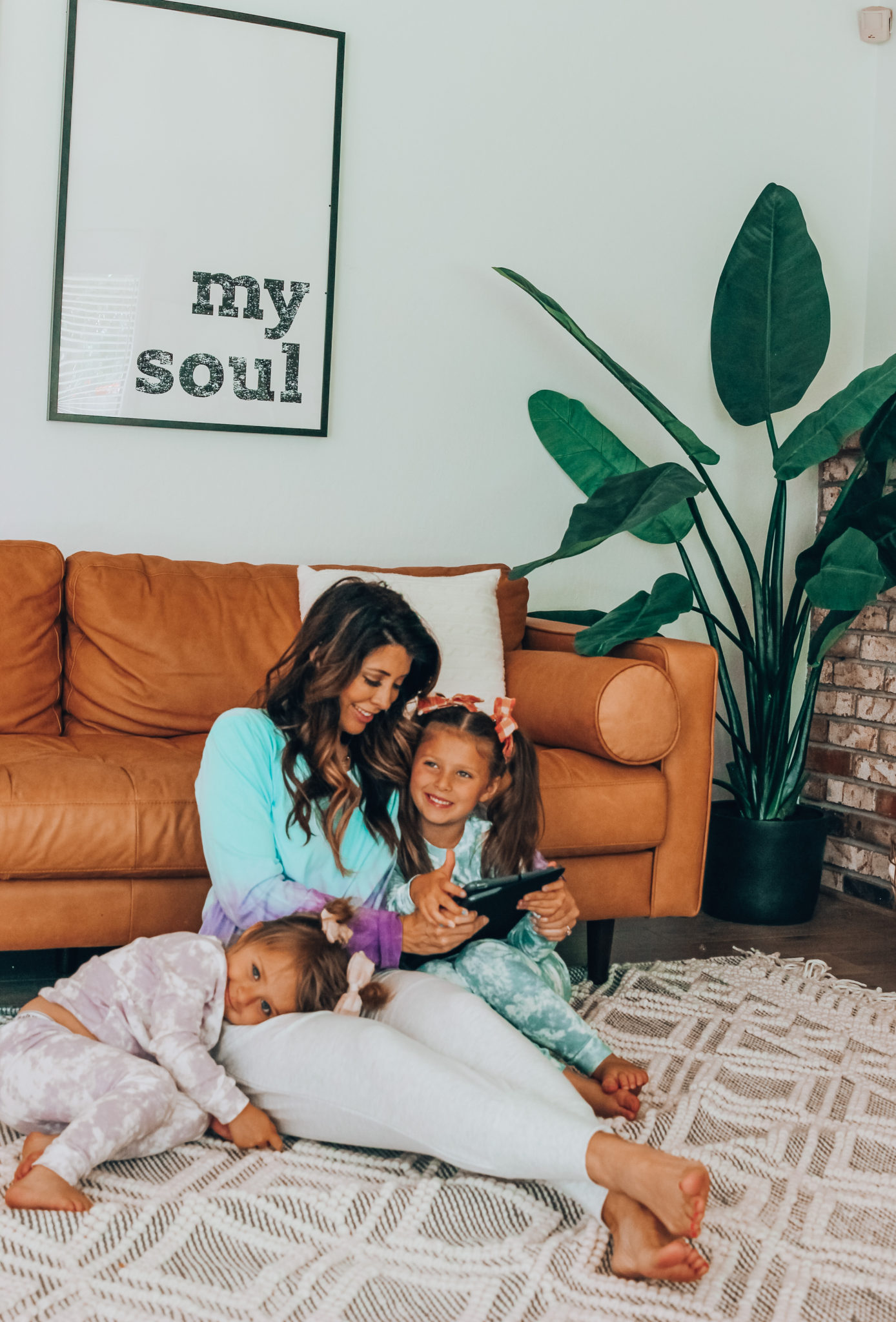 Messenger Kids Review by popular San Francisco lifestyle blog,The Girl in the Yellow Dress: image of a mom and her two young daughters sitting together on the floor and holding a tablet. 