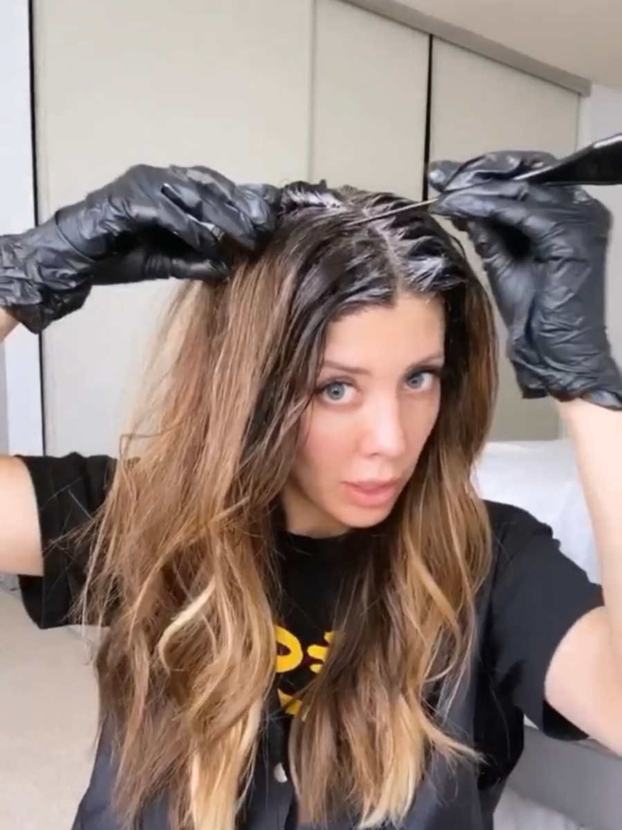 How to Touch Up Roots by popular San Francisco beauty blog, The Girl in the Yellow Dress: image of a woman wearing black Latex gloves and brushing hair dye on her roots. 