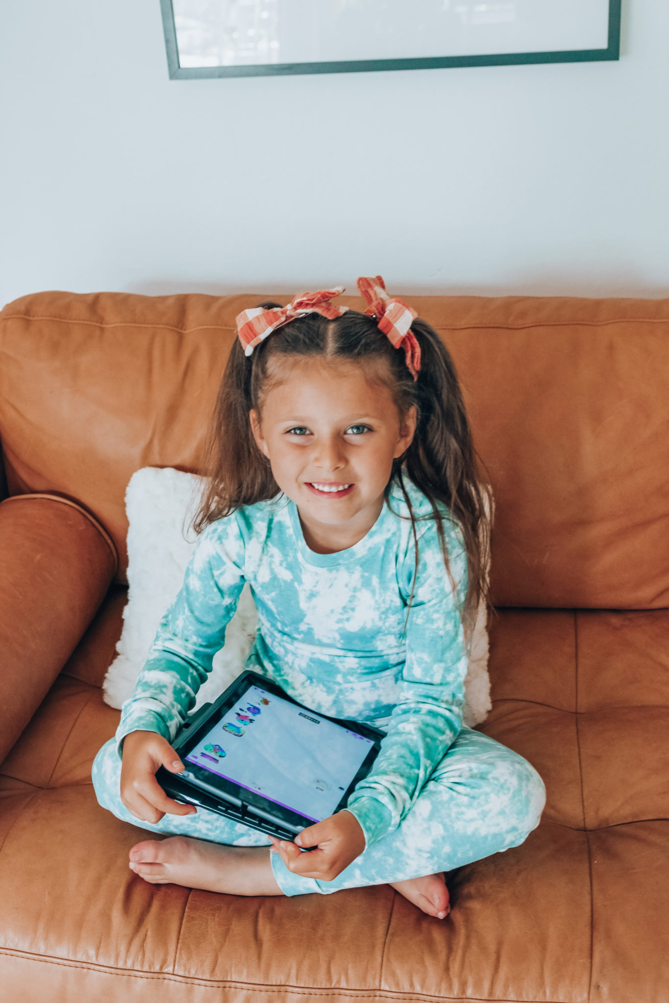 Messenger Kids Review by popular San Francisco lifestyle blog,The Girl in the Yellow Dress: image of a young girl wearing a tie dye pajama set and holding a tablet. 